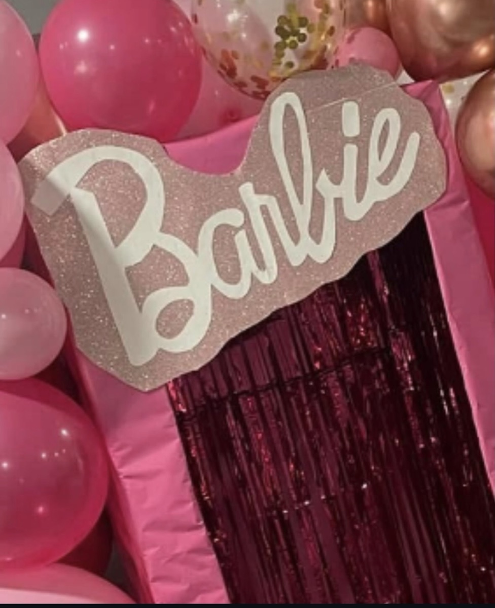 Pink Barbie themed birthday backdrop with pink balloon garland and glitter Barbie sign